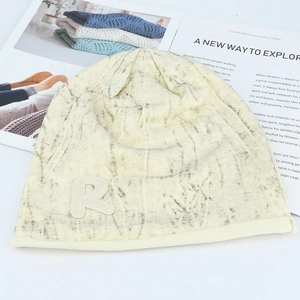 Gros plan du bonnet en maille crème avec motif marbré noir et écusson brodé R