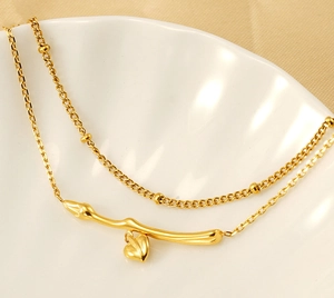 Close-up of golden double-layer necklace with heart pendant in white shell-shaped dish
