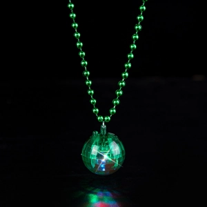Detailed view of the glowing green disco ball pendant necklace on a dark background