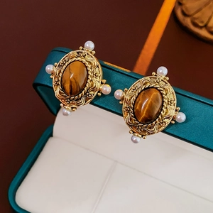 Gros plan de boucles d'oreilles vintage avec œil de tigre et perles en boîte