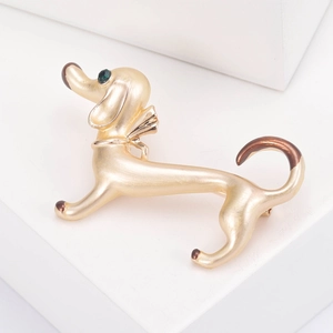 Macro shot of gold dachshund dog brooch with brown details and green rhinestone eye