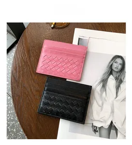 Close-up of woven sheepskin card holders in black and pink on a wooden surface