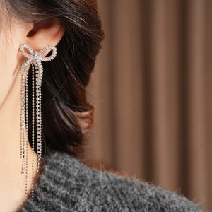 Close-up of 18k gold plated bow tassel earrings with sparkling rhinestones on model