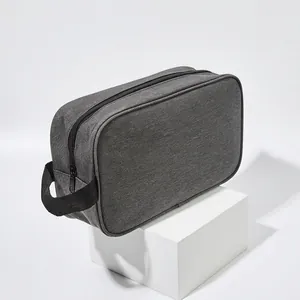 Minimalist grey waterproof oxford cloth travel toiletry bag with black handle on white podium