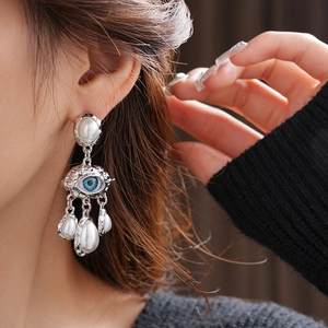 Close-up of vintage silver earrings with pearl fringe and blue eye detail on model