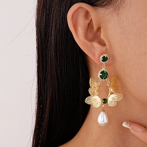 Detailed close-up of double-layer butterfly earring with green zircon and pearl drop