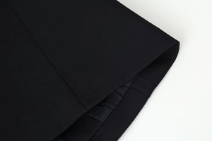 Close-up of high-quality black woven fabric texture and hem on a V-neck long sleeve jacket