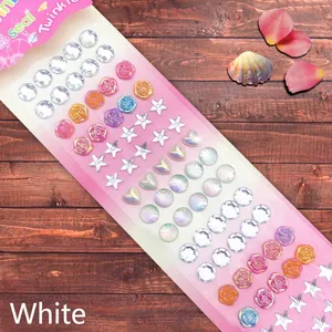 Macro shot of assorted crystal gemstone stickers in star and heart shapes on wood