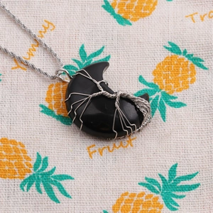 Detail of a crescent moon black stone pendant wrapped in silver wire on rope chain