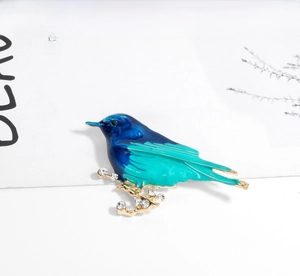 Detail of bird brooch with blue-green enamel, gold branches and sparkling crystals