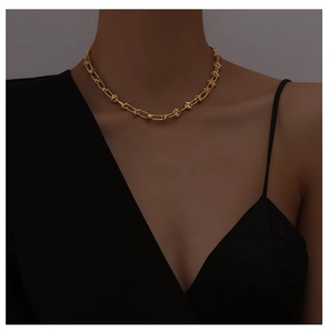 Close-up of minimalist 18K gold knot chain necklace worn by model on dark background