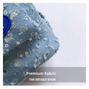 Detail of light blue denim fabric with silver sequins and distressed frayed texture