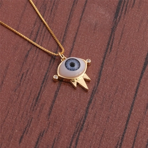 Detail showing an evil eye pendant with blue resin and tiny rhinestones on a gold chain