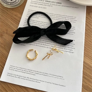 Artistic layout of gold bow stud earrings and fabric bow on decorative background