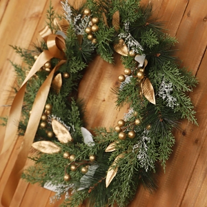 Handcrafted Christmas wreath with golden leaves, berries and ribbon on wood background
