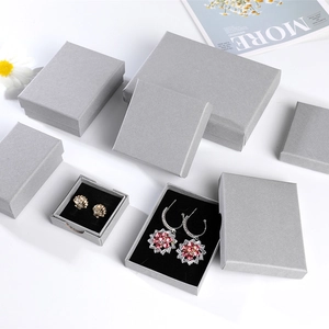 Detailed view of gray textured jewelry gift boxes with gold shell and flower earrings