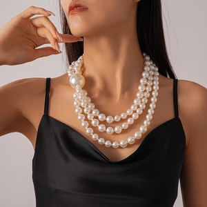 Close-up of triple-layered pearl necklace with large focal pearl on model