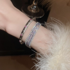 Nahaufnahme von geschichteten Armbändern mit mehrreihigen lila und weißen Kristallen