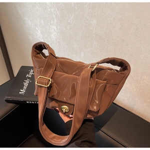 Detailed view of brown quilted glossy leather shoulder bag with gold metal clasp