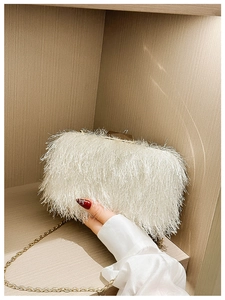 Detailed close-up of white feather clutch bag featuring a sleek gold chain strap