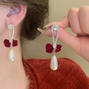 Detailed view of silver stud earrings with red velvet bow and teardrop pearl pendants