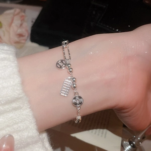 Detailed macro of silver-plated bracelet featuring abacus and ancient coin charms