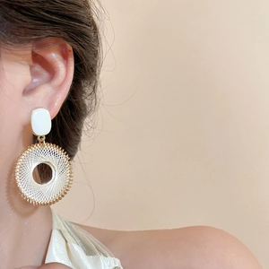 Gros plan de boucles d'oreilles cercles dorés avec fil blanc sur le mannequin