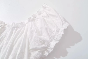 Close-up of white lace embroidery and ruffled elastic neckline on women's dress