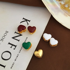 Close-up of gold-plated heart earrings with colorful enamel on a Kinfolk magazine background