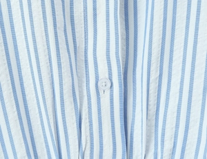 Dettaglio del tessuto di cotone a righe bianche e blu con un bottone a quattro fori