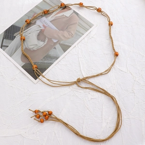 Detail of adjustable khaki woven waist chain with wooden beads and tassel decoration