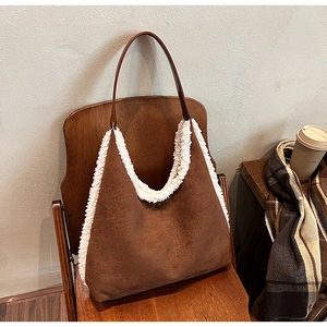 Brown faux suede tote bag with white faux fur trim placed on a dark wooden chair