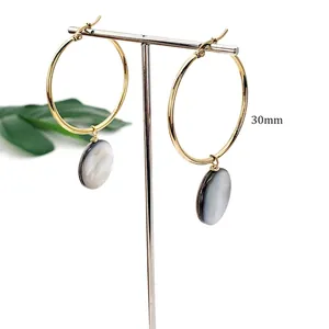 Detail of 30mm gold hoop earrings with round iridescent natural black shell pendants