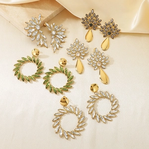 Flat lay detail of assorted gold stainless steel earrings with crystals on silk fabric