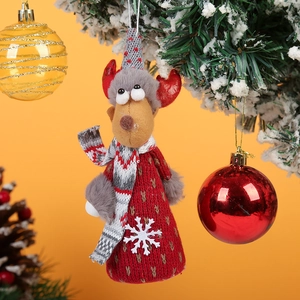 Close-up of a reindeer ornament with red knit sweater hanging on a snowy Christmas tree