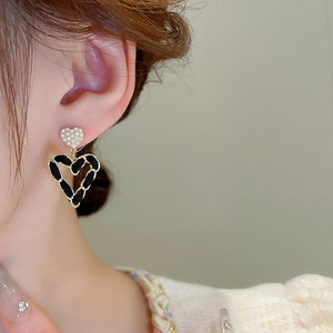 Detail of vintage heart earrings with faux pearl studs and black leather woven gold chain