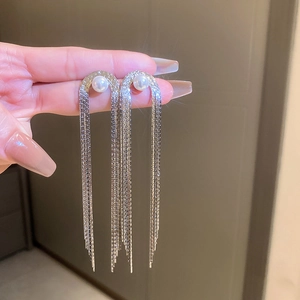 Detail shot of silver multi-strand chain tassel earrings featuring a white round pearl