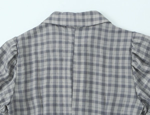 Detail view of grey plaid dress featuring back neckline and pleated puff sleeve design