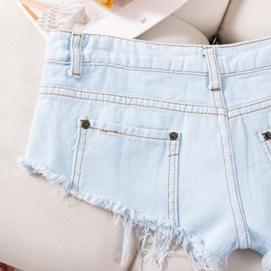 Details von hellblauen Denim-Shorts mit ausgefransten Kanten und silbernen Metallnieten