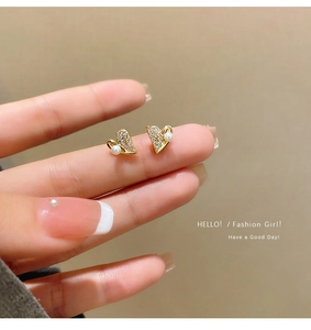 Close-up of gold heart earrings with micro-set zircons and a small white pearl detail
