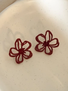 Nahaufnahme der roten hohlen Blumenohrstecker auf einem weißen Keramikteller