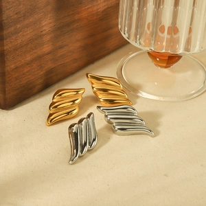 Polished angel wing earrings in gold and silver finish on elegant wooden background