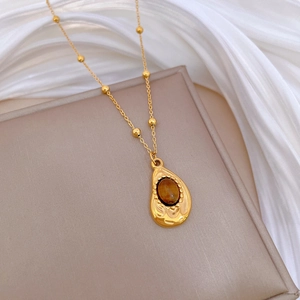 Gold beaded chain necklace featuring an irregular teardrop brown gemstone pendant