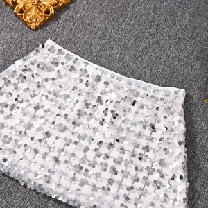 Detail eines silbernen Paillettenrock mit elastischem Bund und Netzfutter auf grauem Teppich