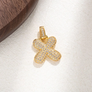 Macro shot of gold cross pendant with micro-pave cubic zirconia on a textured surface