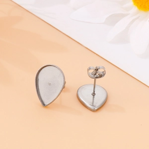 Silver teardrop stainless steel stud earrings on an orange backdrop with floral accents