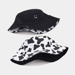 Reversible bucket hat featuring cow print and black side with smile embroidery