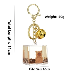 Detail view of Kapybara quicksand keychain with liquid-filled square bottle and golden bell
