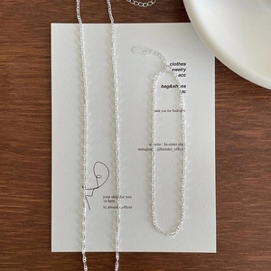 Detail shot of minimalist S925 sterling silver anklet chains on a wooden surface