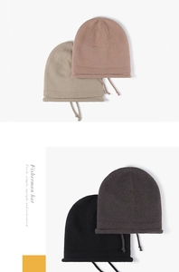 Close-up of thick knitted beanies in pink and grey showing textured weave and drawstring